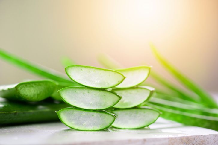 Cut leaves and slices of aloe vera on a white surface