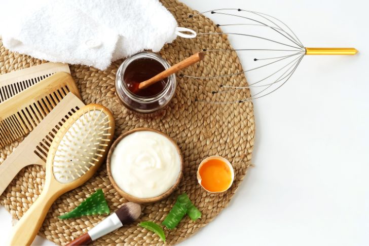Homemade hair mask and ingredients for hair growth: honey, egg, yogurt, aloe on white background.