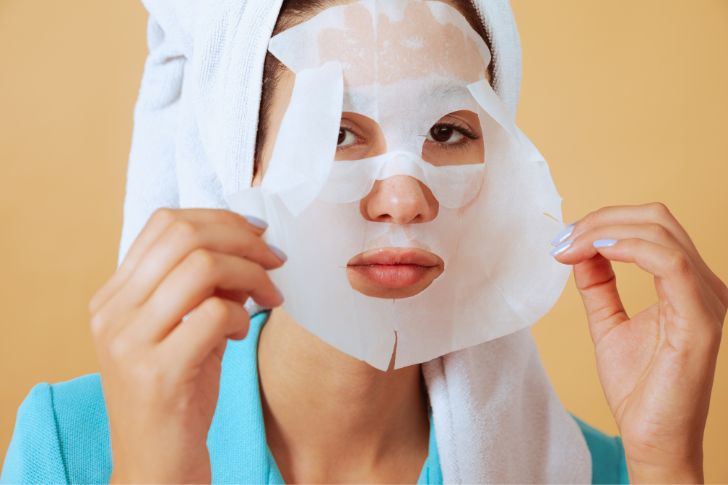 Girl using sheet mask for skin care routine.