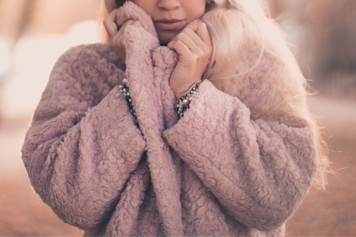 Beautiful woman wearing a cozy pink fur coat outdoors over sunny background. Winter season.