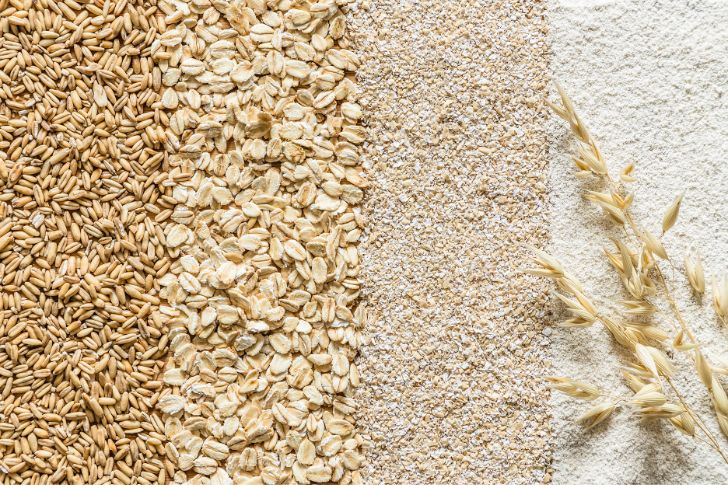 Top view of various types of oatmeal arranged on vertical strips: oat grain, oat flakes, oat bran and oat flour background.