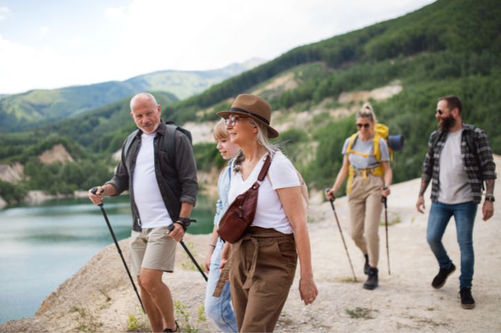 Summer bucket list: Happy multigeneration family on hiking trip on summer holiday, walking.